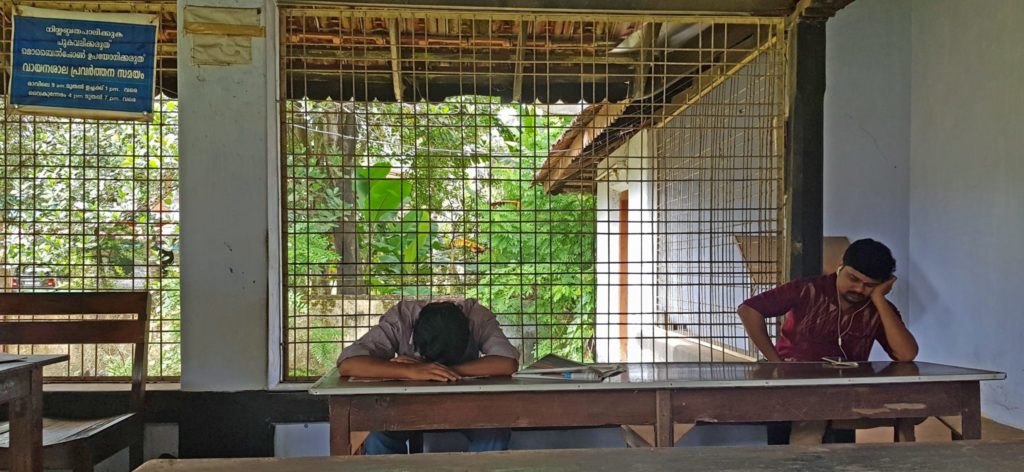 Scene from a reading room in Thrissur district, central Kerala
Sign on the top left reads: ‘Maintain silence, Do not smoke, Do not use mobile phones.’ Two men sit at benches, one with his head down on the desk, another staring at a mobile device on the bench, with earphones on.