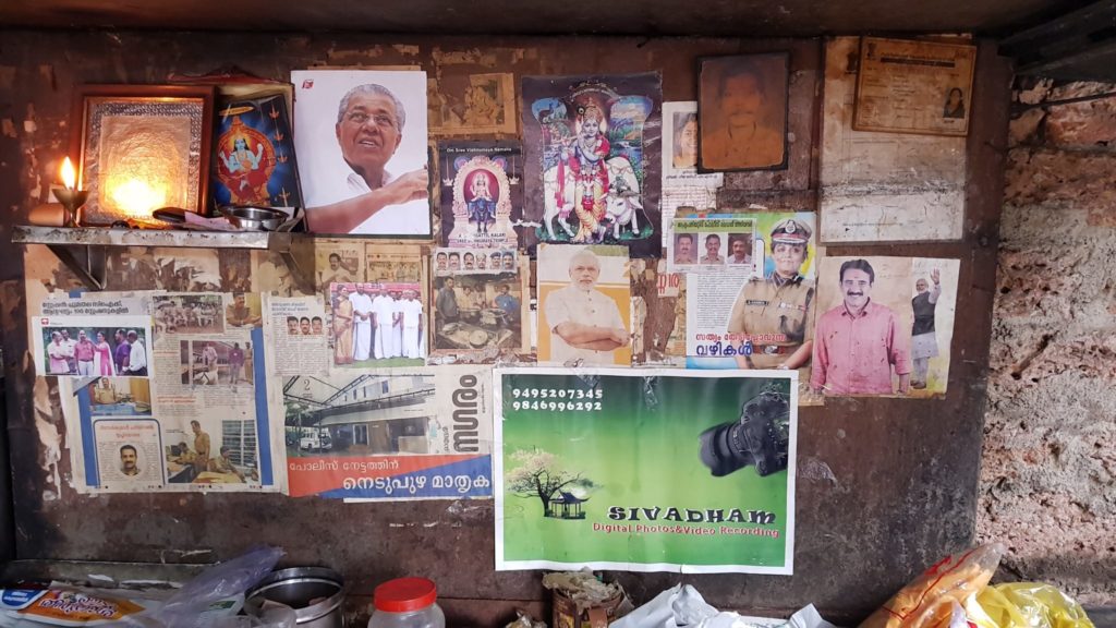 A Collage of paper clippings, politician images and hindu idols on a wall. 